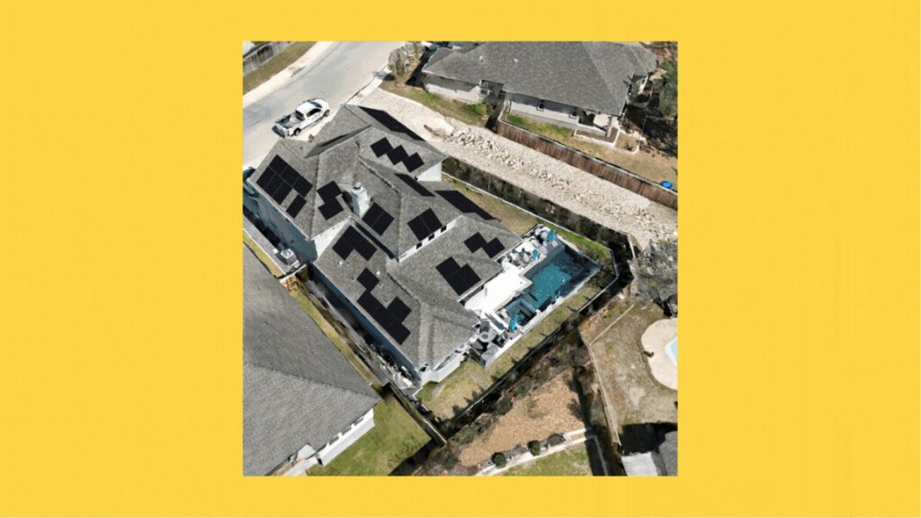 An aerial view of a house with a dark gray roof, white walls, and a blue pool, situated in a suburban neighborhood with a stone driveway.